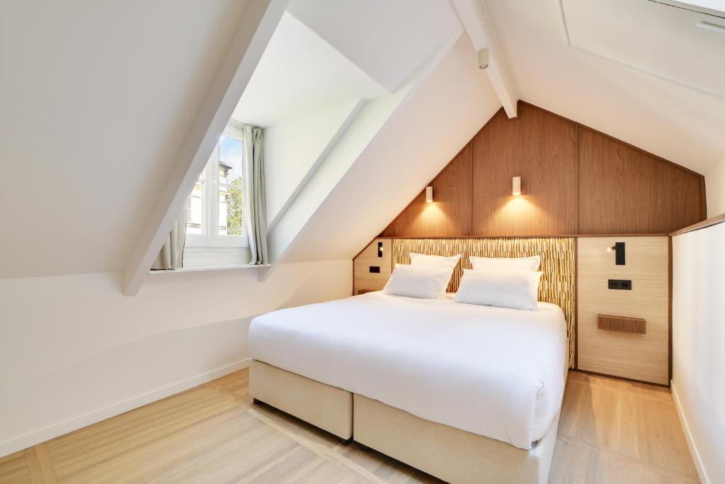 a bedroom with a white bed and a window at Hotel Murmures Notre-Dame in Paris