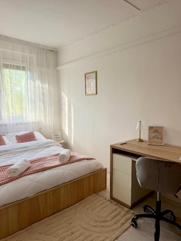 a white bedroom with a bed and a desk at 2-6 Apartman Szeged in Szeged