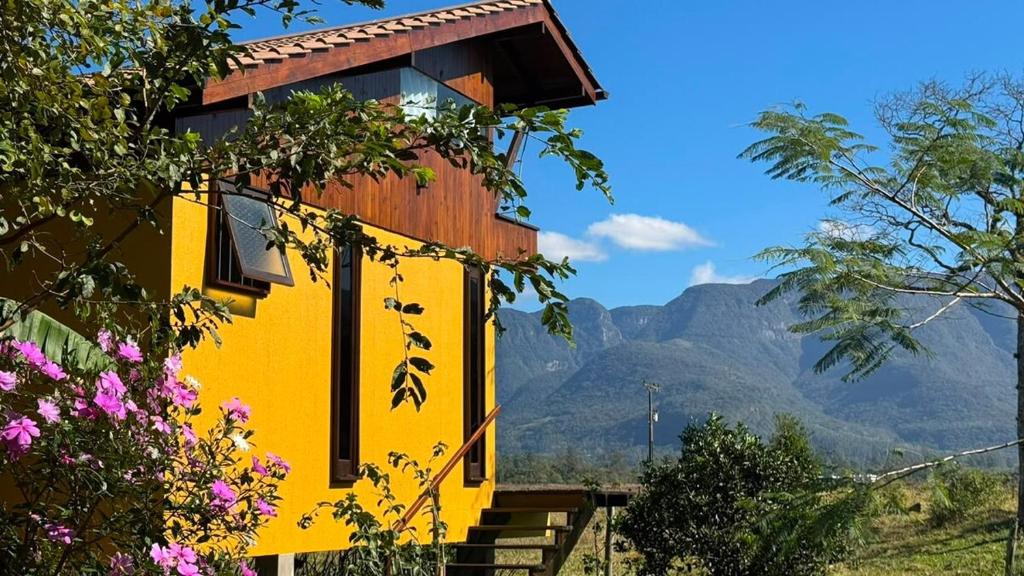 a yellow house with mountains in the background at Cabana Flamboyant in Praia Grande