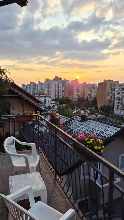 a balcony with white chairs and flowers on a building at Cherry Apartments in Sarajevo