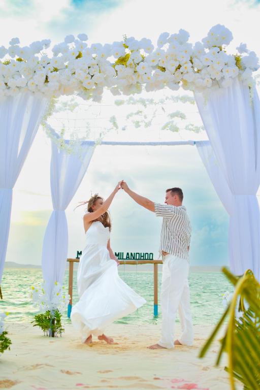 a bride and groom dancing under a wedding arch on the beach at Handhuvaru Maldives in Milandu