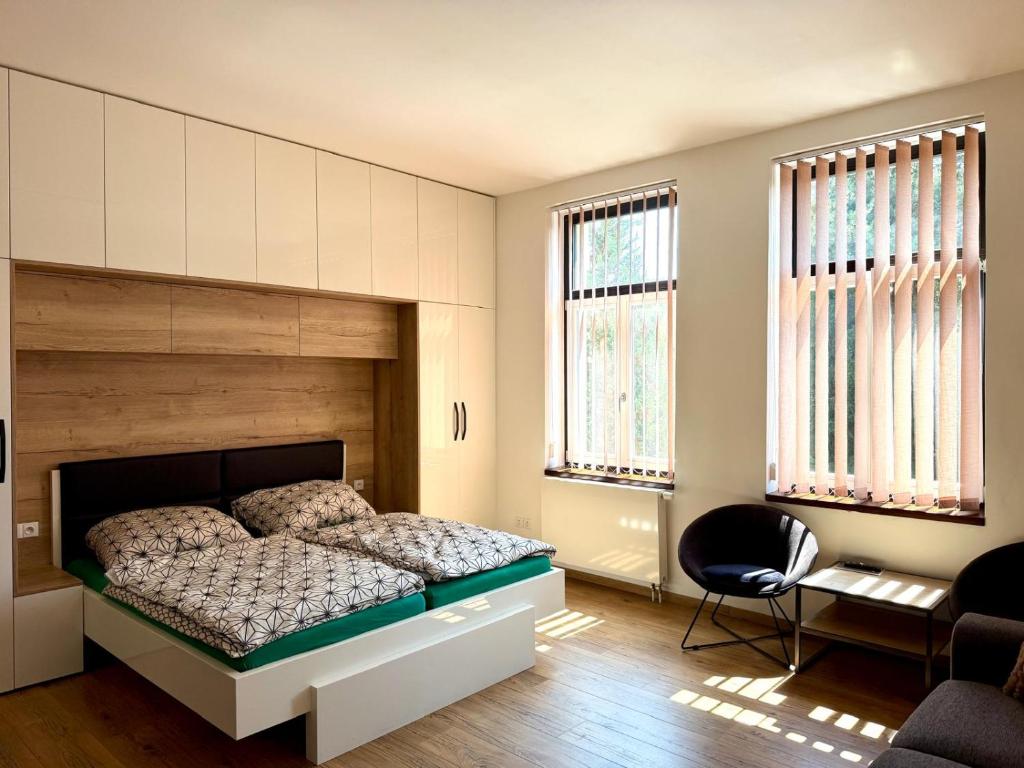a bedroom with a bed and a chair and windows at Apartmán Palza Jablonec in Jablonec nad Nisou