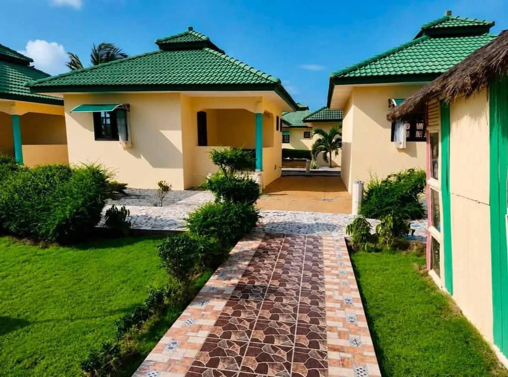 a house with a brick walkway in front of it at Nima Resort et Suites in Mandanou