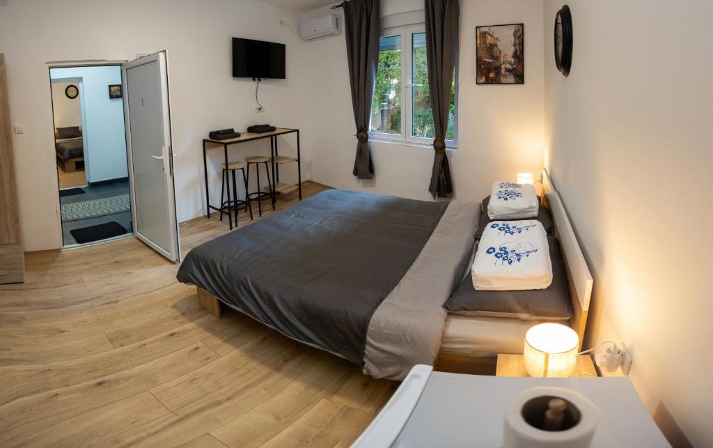 a bedroom with a bed and a table and a window at Naissus Apartments in Niš