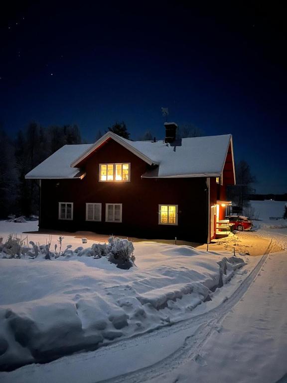 a house with lights on in the snow at night at Historic lakeside villa - sauna, ski, boat, 20 guests in Sunnansjö
