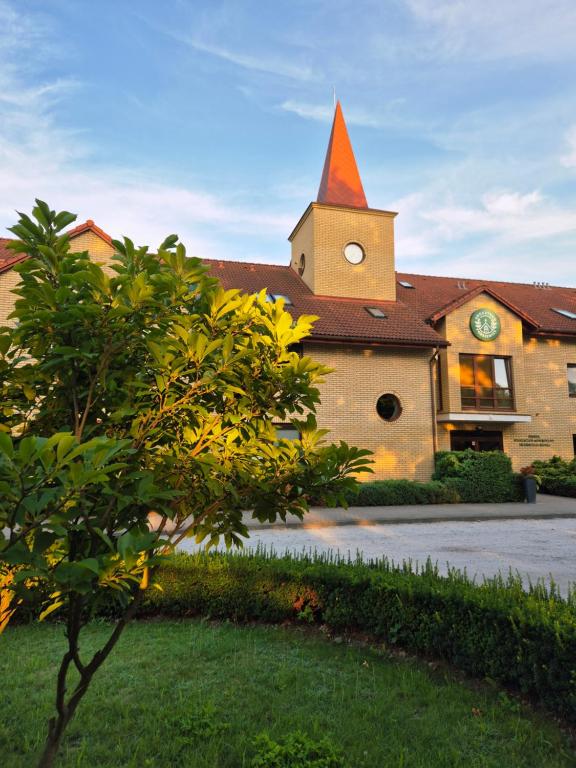 a building with a church with a clock tower at Uroczysko Porszewice - Ośrodek Rekolekcyjno-Konferencyjny koło Łodzi in Łódź