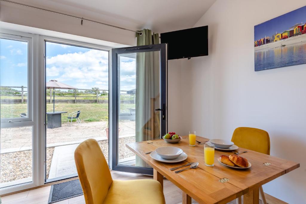 a dining room with a wooden table and a sliding glass door at Kent Coast Stays - Cottages in Birchington