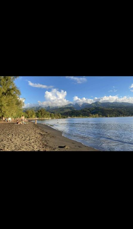 a beach with people sitting on the sand and water at Uvini's Mahina Lodge in Mahina