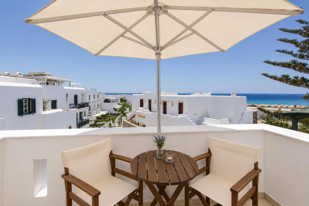a table and chairs on a balcony with an umbrella at Welcome Naxos in Agios Prokopios