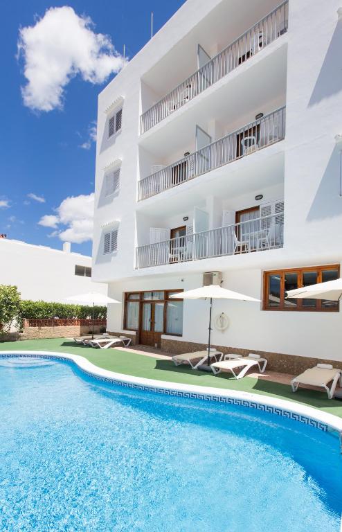 a villa with a swimming pool in front of a building at Apartamentos Sofía in Es Cana