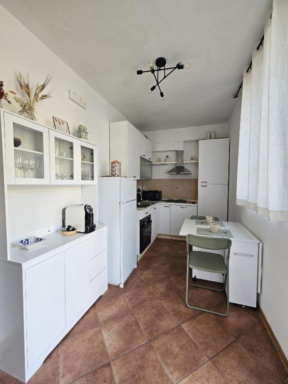 a kitchen with white cabinets and a table with a chair at La sosta di Strada in Strada