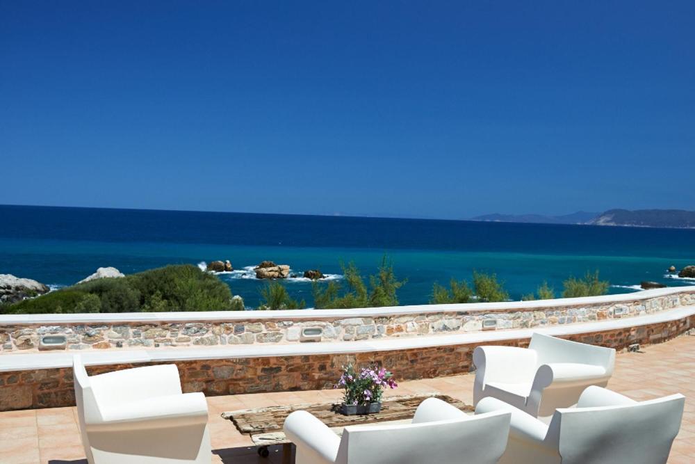 a patio with white chairs and a view of the ocean at St George's House in Potistika