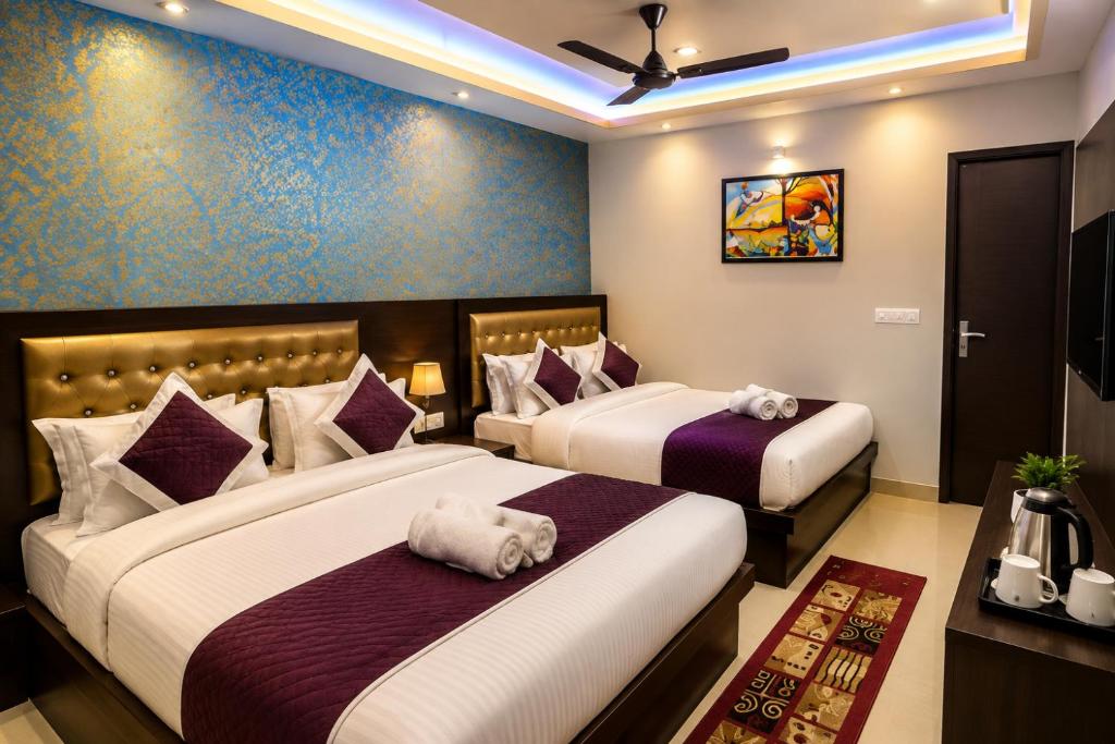 two beds in a hotel room with purple walls at Hotel Bed & Room in Agra