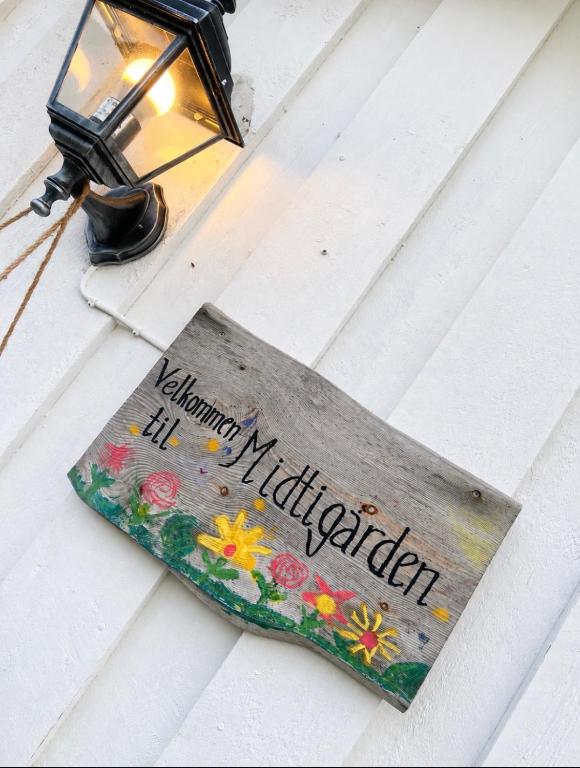 a sign on a table with a light and flowers on it at Midtigården in Teksdal