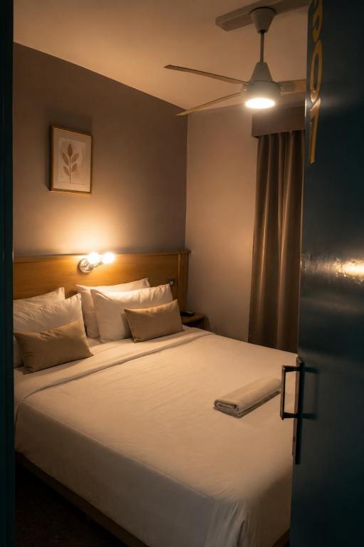 a bedroom with a large white bed with a ceiling fan at Hotel JBJ in Mendoza