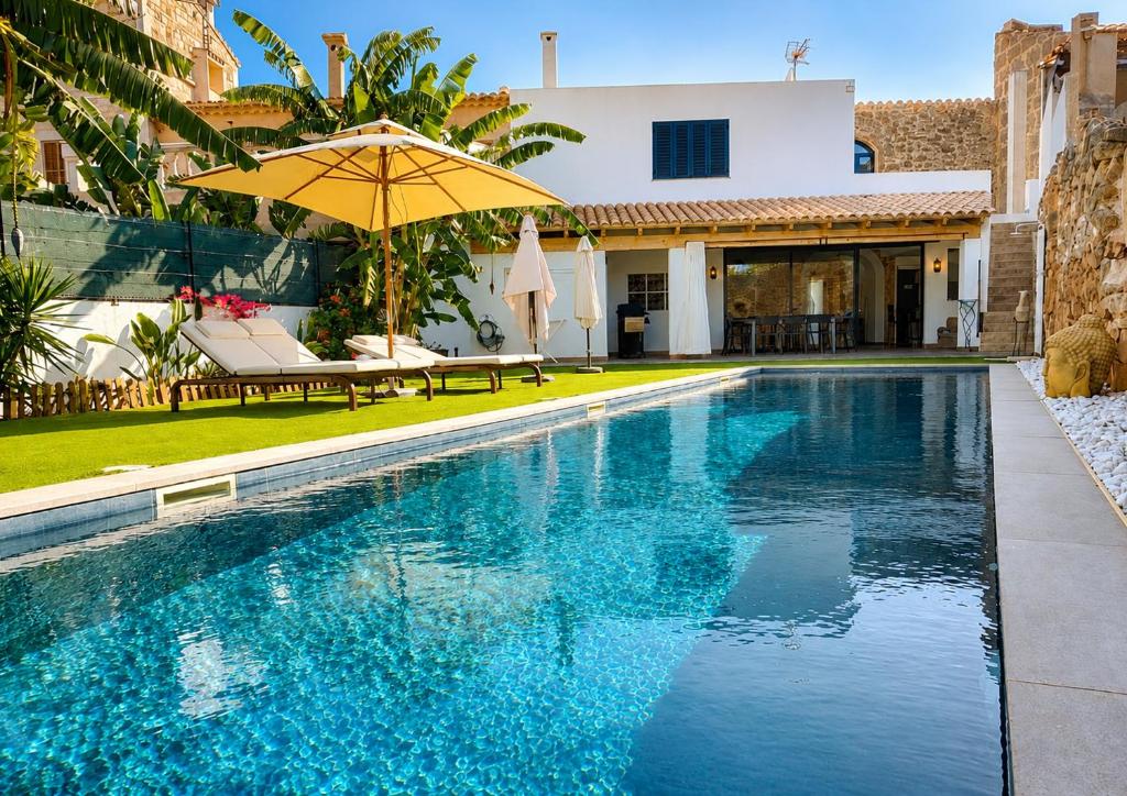 a swimming pool with an umbrella next to a house at Can Roig in Ses Salines