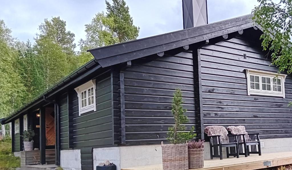a black house with two chairs in front of it at Bjorlicabin in Bjorli