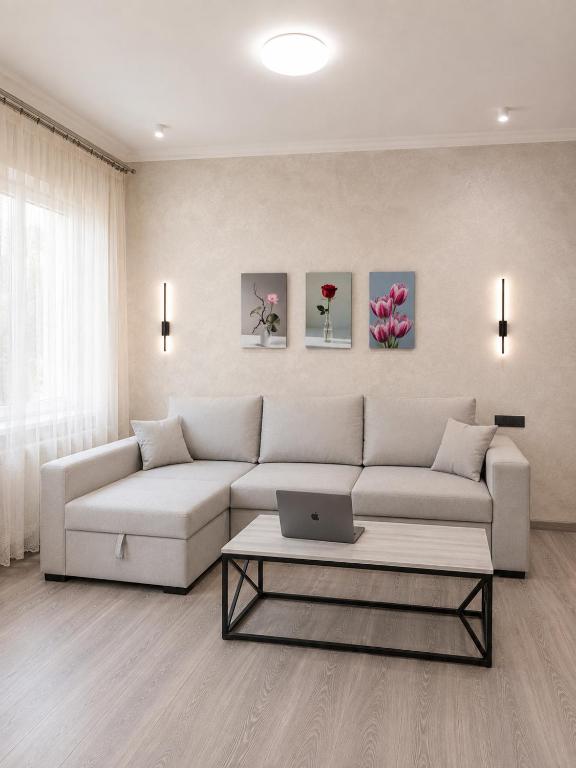 a living room with a couch and a laptop on a coffee table at Cozy Apartment on the First Floor in Yunusobod