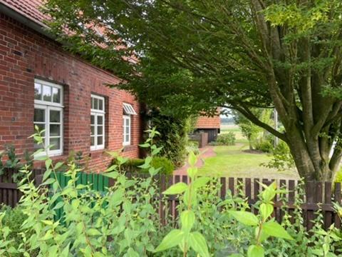 a red brick house with a tree and a fence at Prinzenvilla in Berge