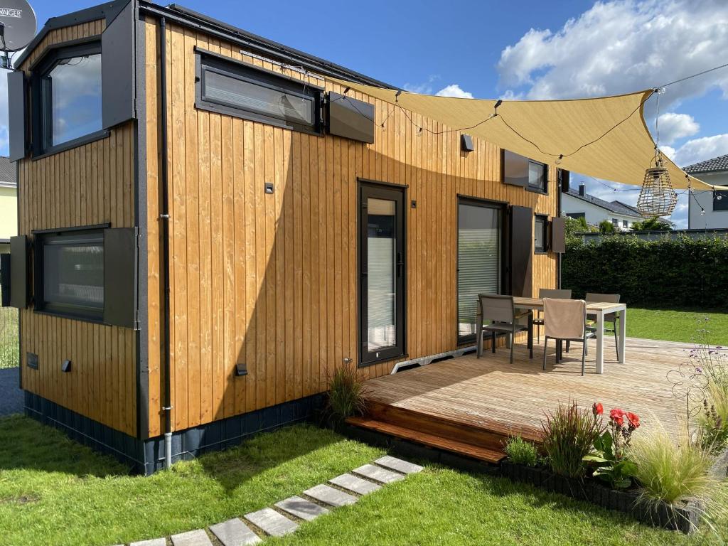a tiny house with a deck and a table at Tiny House WICA in Königs Wusterhausen