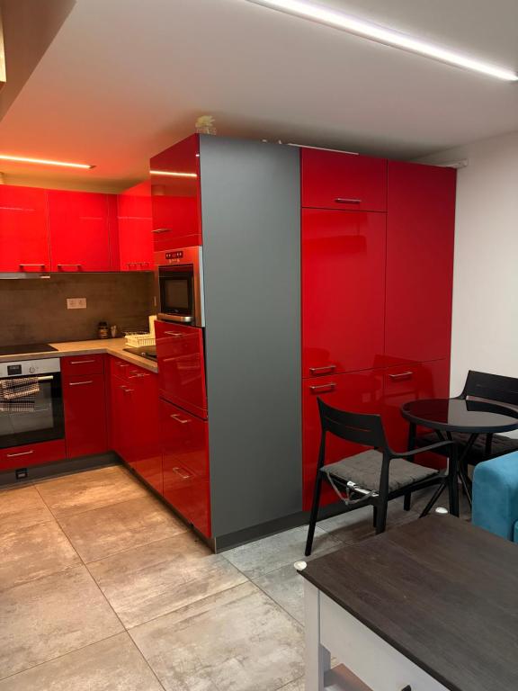 a kitchen with red cabinets and a dining table at Apartmán 2 in Zlín