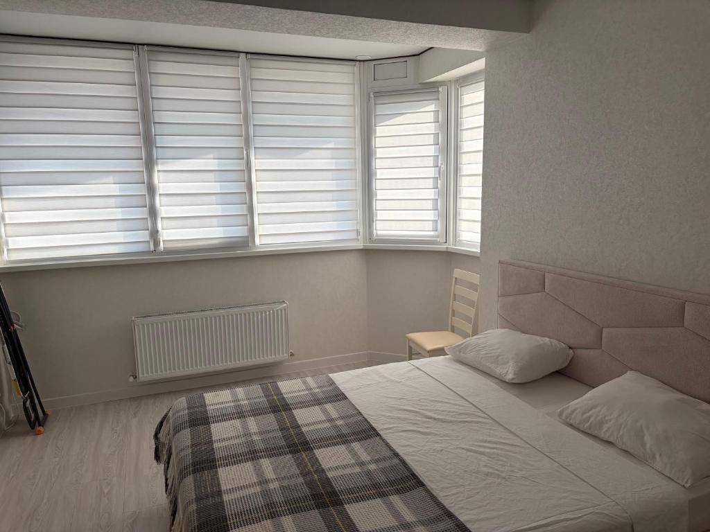 a bedroom with a bed and two windows at Apartament in Chişinău