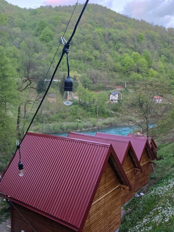 a red roofed house with a river in the background at Adventure Tara in Foča