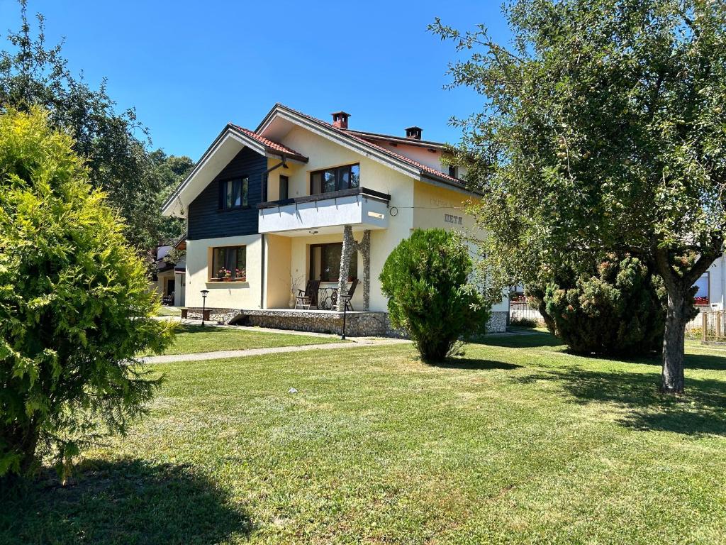 a house with a lawn and trees in front of it at Къща Петя село Орешак in Troyan