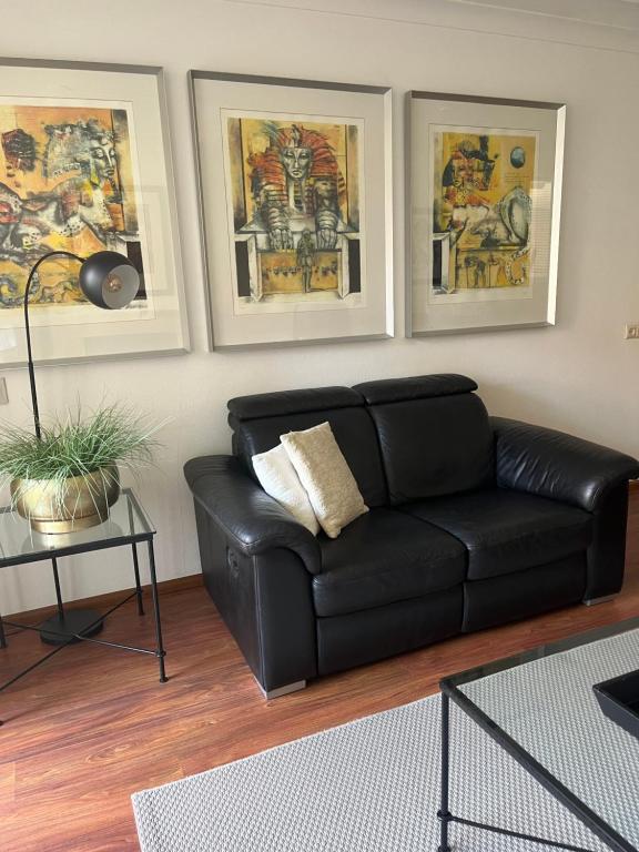 a black leather couch in a living room with paintings at Franciscus in Bergen op Zoom
