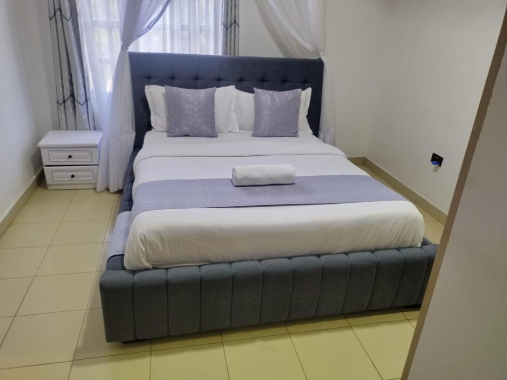 a bedroom with a large bed with a blue headboard at Gee homestay Kakamega in Kakamega