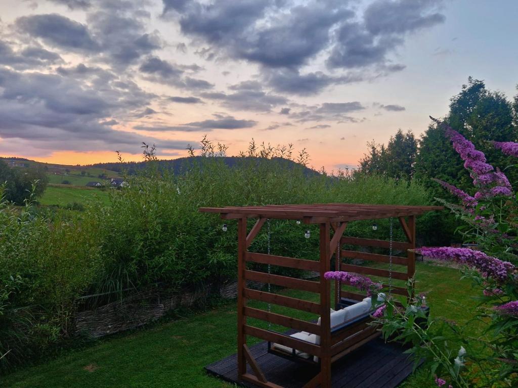 a wooden bench sitting in a garden with purple flowers at Bieszczady Kwatery u Pączka in Bukowiec