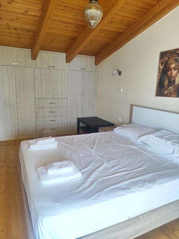 a large white bed in a room with a wooden ceiling at Maisonette Kalypso in Diakopto