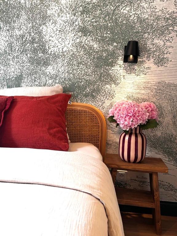 a bedroom with a bed and a vase of flowers on a table at L'Adresse Studio Rempart sud - centre historique Eguisheim in Eguisheim