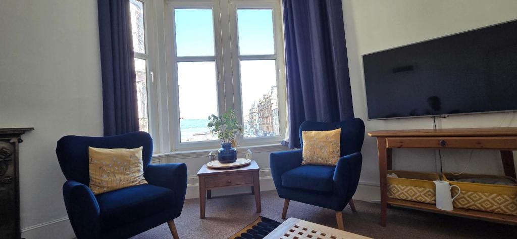 a living room with two blue chairs and a television at Bishop Street Apartment in Rothesay