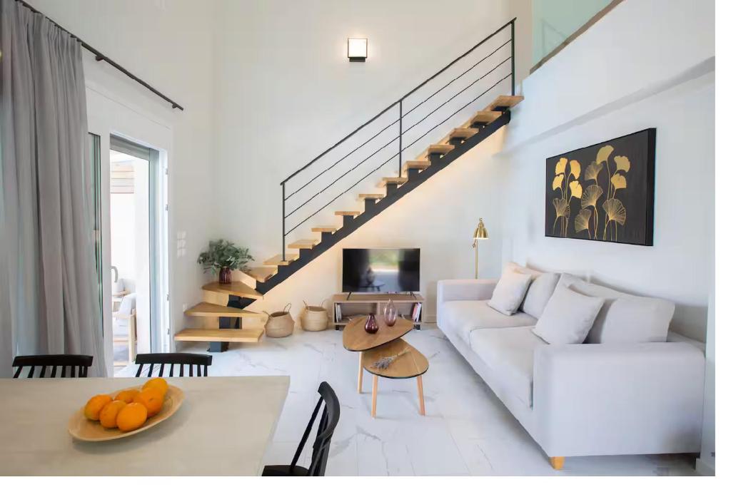 a white living room with a white couch and stairs at Dante Home's in Corfu