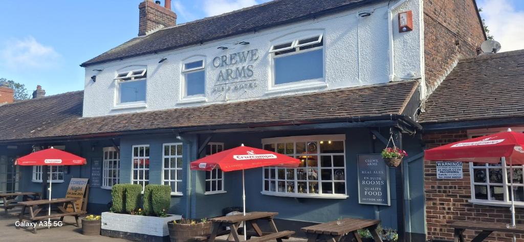 a blue building with red umbrellas in front of it at The Crewe Arms Hotel in Crewe