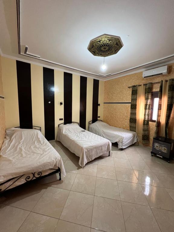 a bedroom with two beds and a wall with stripes at Merzouga Roms in Merzouga