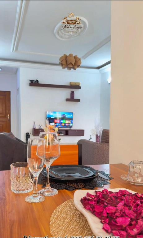 a table with wine glasses and roses on it at Le nid des Anges in Yaoundé