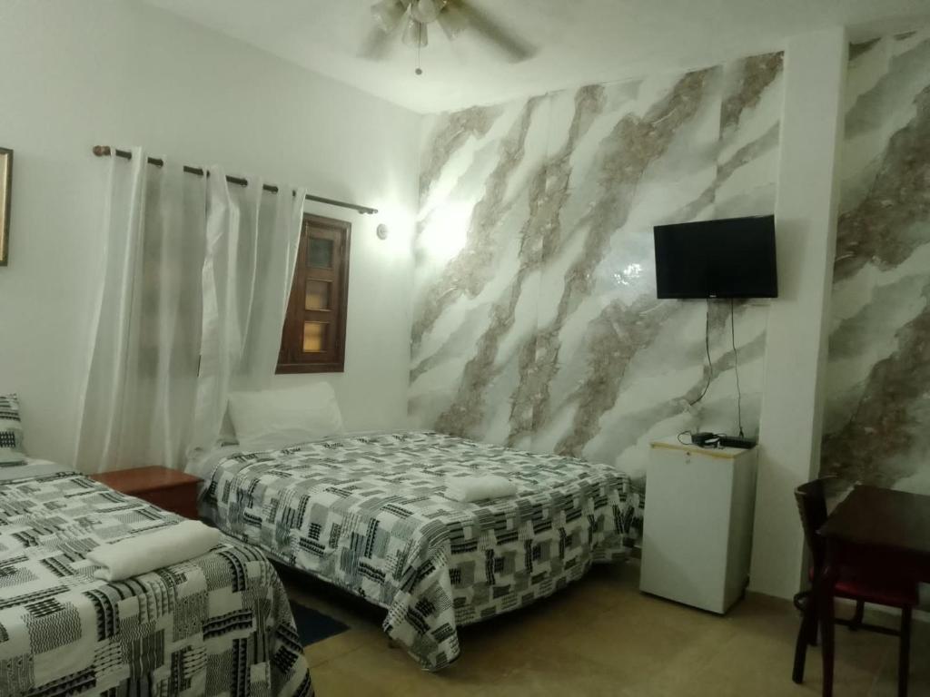 a hotel room with two beds and a tv at Hotel Aluge in Santo Domingo