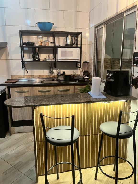 a kitchen with two bar stools and a counter at Casa em Marataízes - Espírito Santo in Marataizes