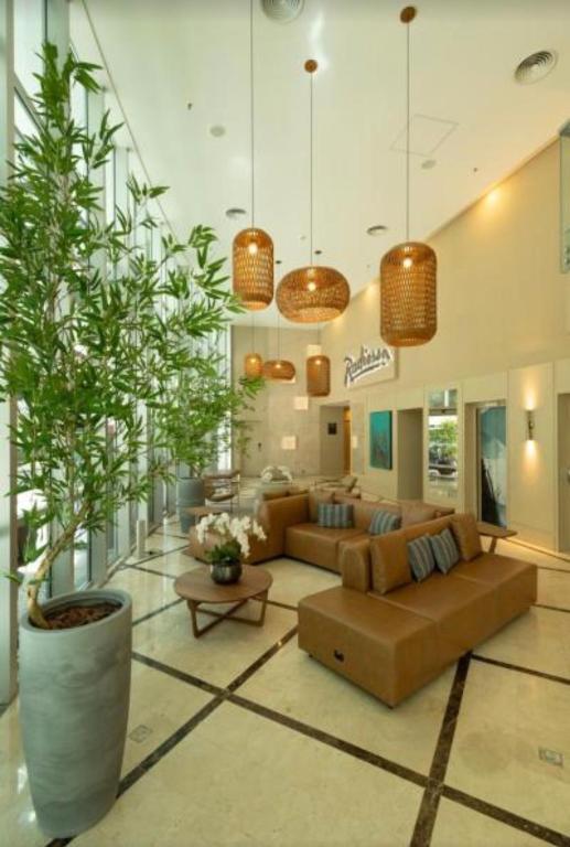 a large living room with couches and plants in it at Radisson V Olimpia in São Paulo