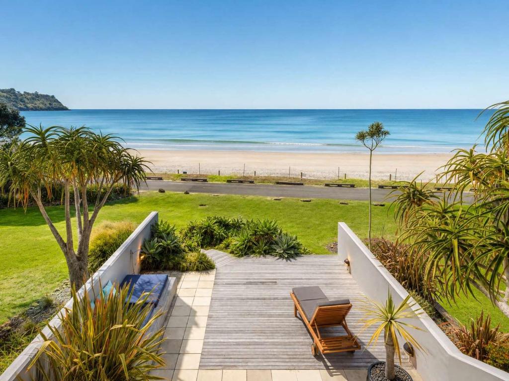 a wooden walkway leading to a beach with palm trees at The Sands - Villa 28 - Stay Waiheke in Onetangi