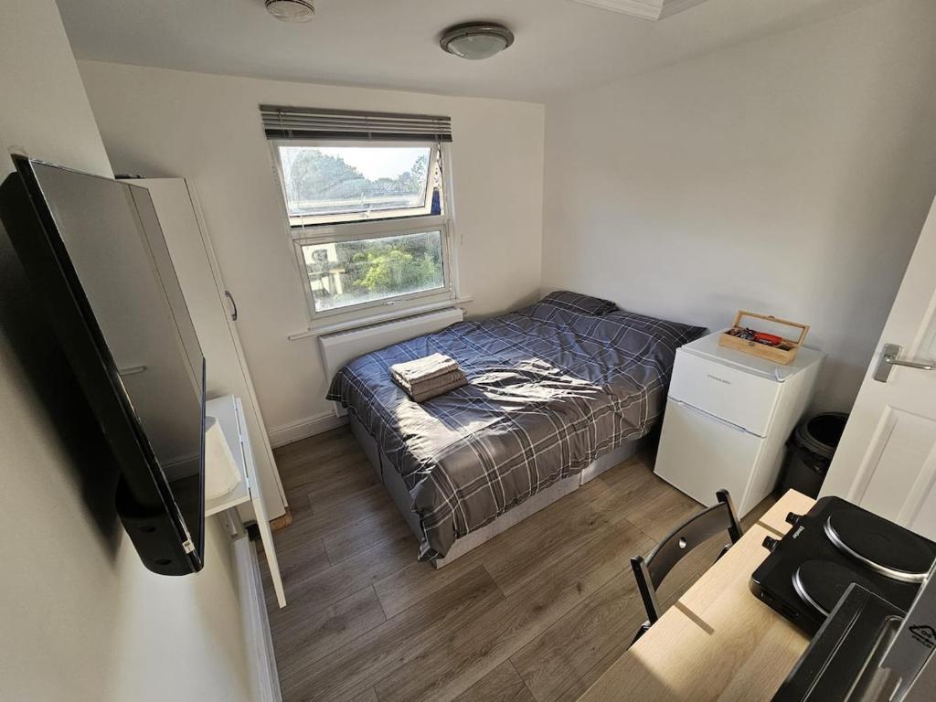 a small bedroom with a bed and a window at Modern Fully Contained En-Suite Room With Kitchen in Sidcup