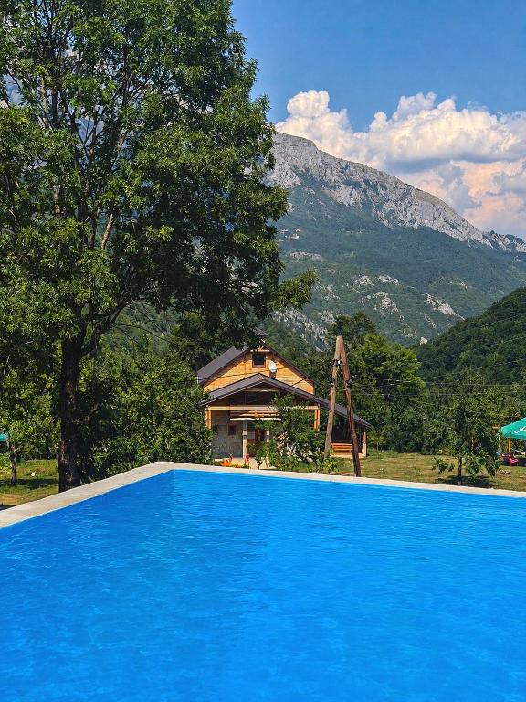 a blue swimming pool with a house and a mountain at Etno domaćinstvo Dvožak in Plužine