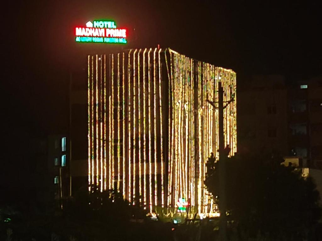 a tall building with a cross and a neon sign at HoTEL MADHAVI PRIME in Guntūr