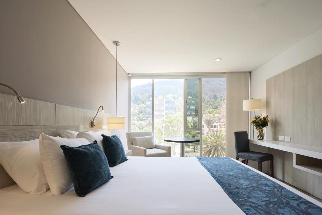 a bedroom with a large bed with a large window at Hotel bh Bicentenario in Bogotá