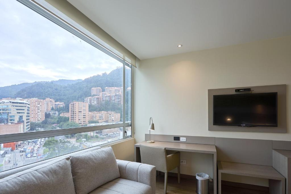 a living room with a couch and a large window at Hotel bh Usaquén in Bogotá