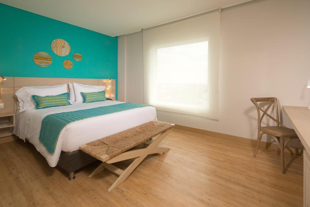 a bedroom with a bed and a desk and a window at bh Barranquilla in Barranquilla