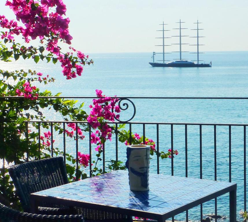 a table with a cup on a balcony with a ship in the water at Hotel Palladio in Giardini Naxos