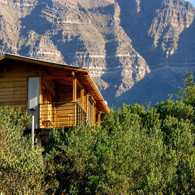 a wooden cabin with a mountain in the background at Refugio Cordillera Flora endógena Bosque Esclerófilo in San José de Maipo